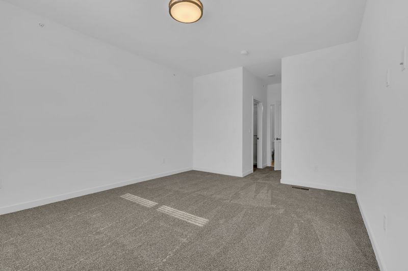 Photo of a bedroom at Edison Lights featuring lush wall to wall carpeting. The entry door and walk in closets can be seen in the background.