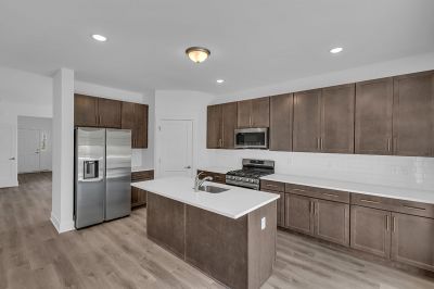 Interior image of a townhome at the Club at Woodhaven showing the kitchen which features new cabinets, stainless steel appliances and an island with sink.