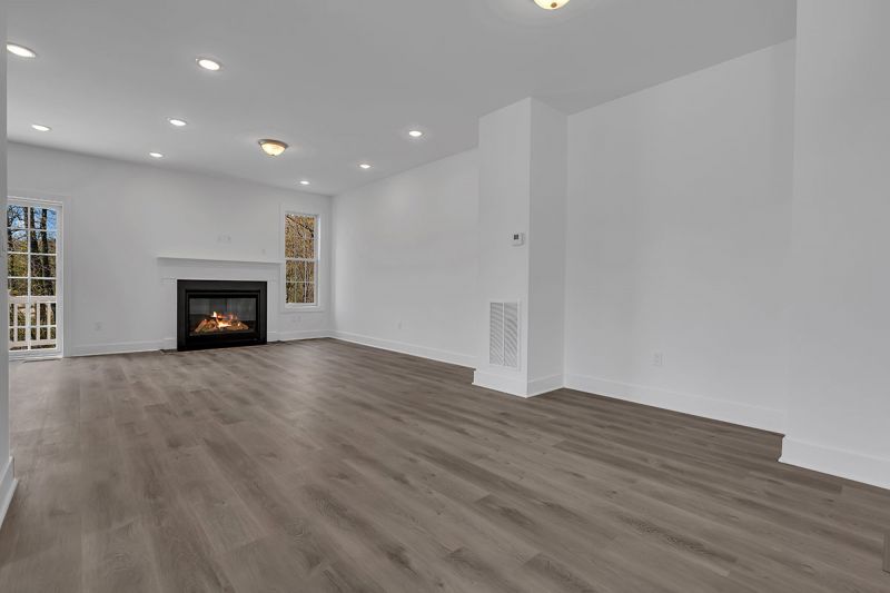 Interior image of a townhome at the Club at Woodhaven showing the large living room with luxury vinyl plank flooring and fireplace.