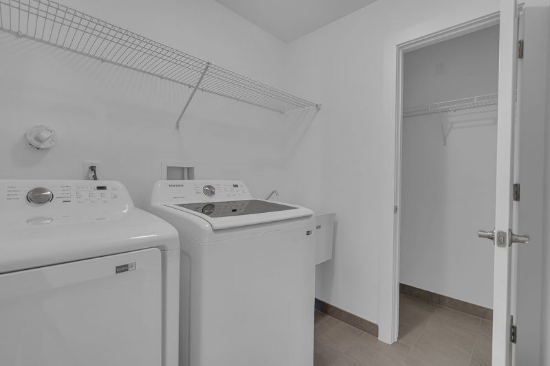 Interior image of a townhome at the Club at Woodhaven showing the full size, side by side, washer and dryer with storage shelf above and storage closet next to it.