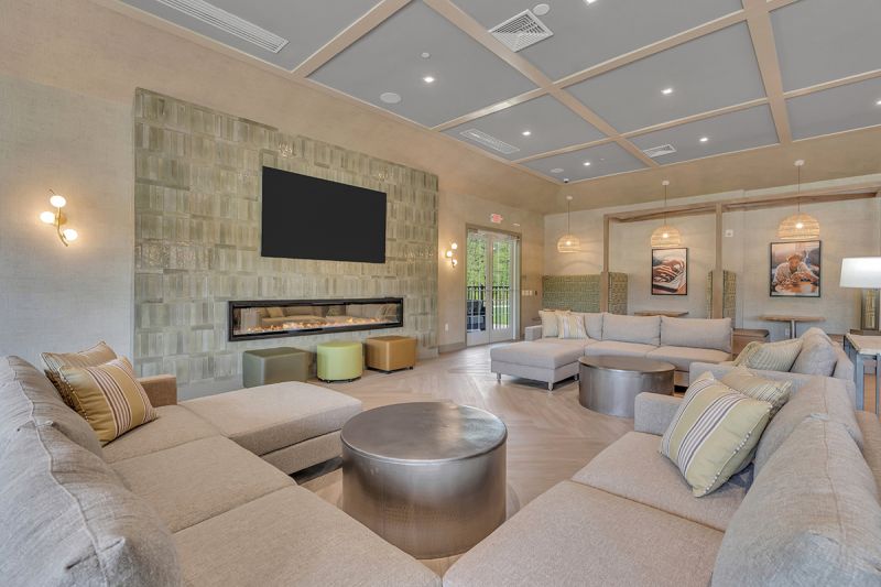 Interior photo of the community room inside the clubhouse at Woodhaven, showing the comfortable seating areas in front of the large fireplace
