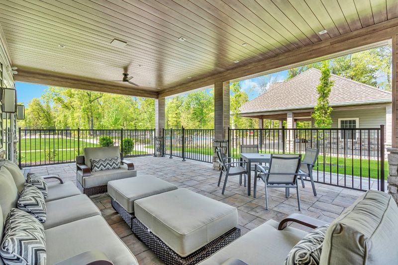 Exterior photo of the poll at the clubhouse at Woodhaven, showing a large swimming pool surrounded by ample seating and a pool house.