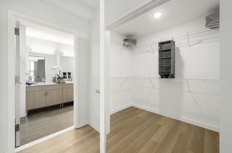 Interior photo showing a walk in closet in an apartment at RVR with luxury vinyl plank flooring and plenty of shelving.