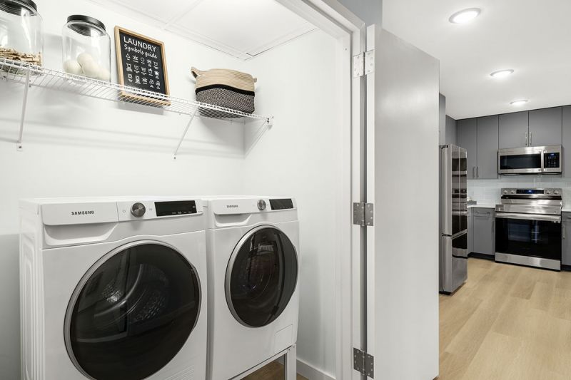 Interior photo showing full size washer and dryer in a private laundry closet off of the kitchen