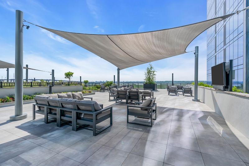 Exterior photo of the rooftop located on the 5th floor at RVR showing shaded seating area with modern outdoor seats with a mounted TV overlooking the amazing views.