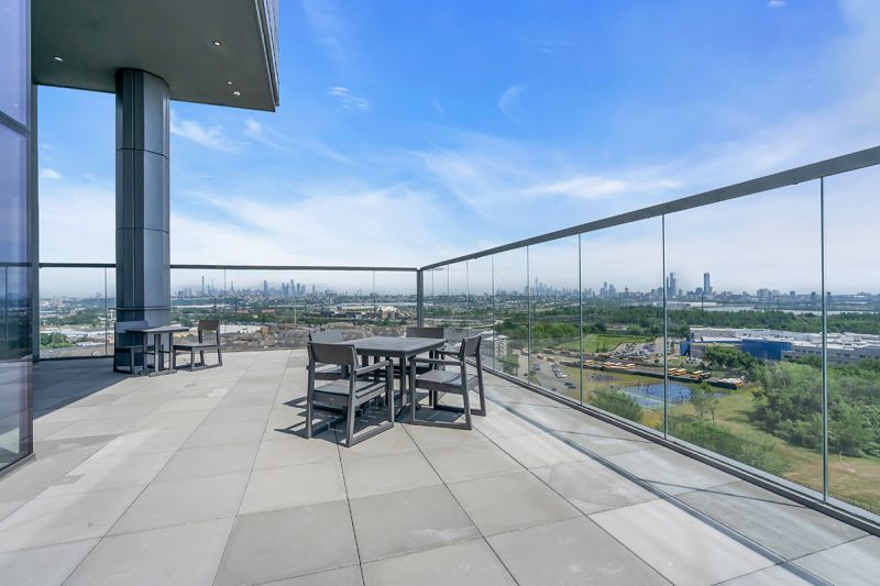 Exterior photo of the rooftop located on the 19th floor at RVR showing another angle of the lounge area with two and four-person seating areas surrounded by clear glass fence overlooking amazing views.