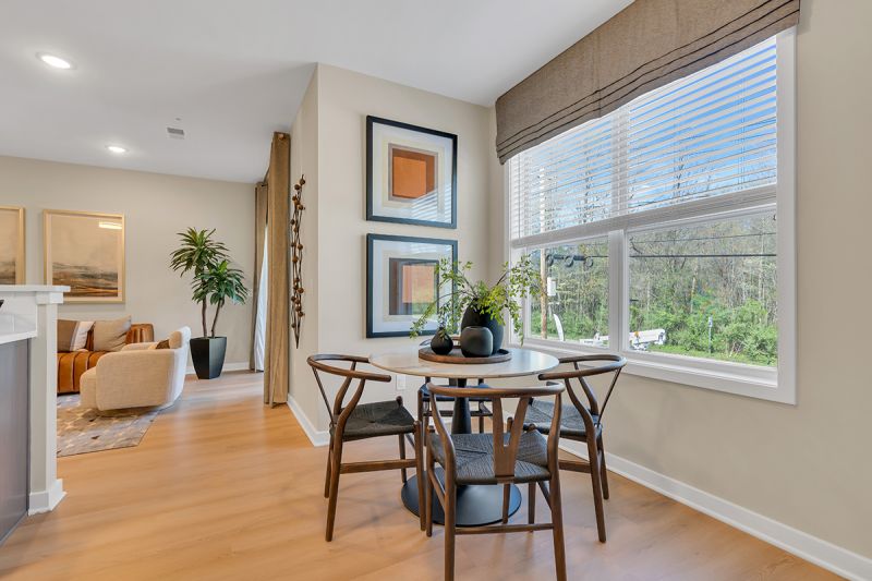 Interior photo of the Boulders at Beekman showing the eat-in dining area with luxury vinyl flooring and a round table for 4 placed in front of a double window which allows for natural light.