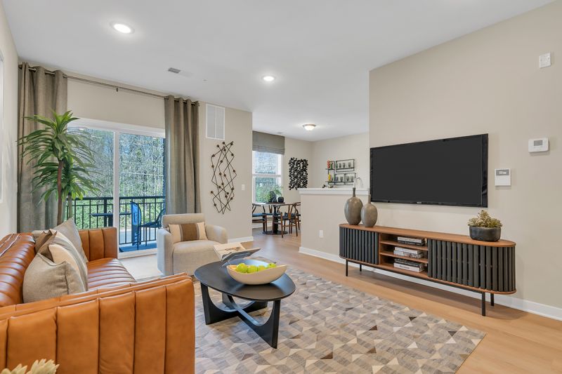 Interior photo of the Boulders at Beekman showing the living room with luxury vinyl flooring, a wall mounted tv, couch, chair and area rug.