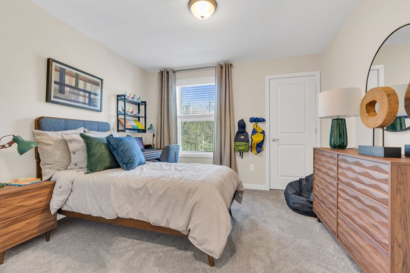 Interior photo of the Boulders at Beekman showing a bedroom with a bed, night stand, dresser, desk, wall to wall carpeting and a window to allow for natural light.