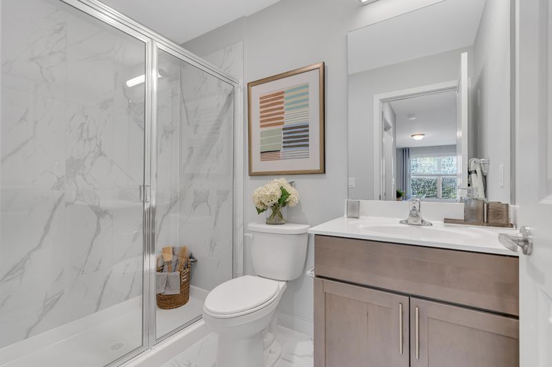 Interior photo of the Boulders at Beekman showing a bathroom with tile flooring, stand up shower, vanity with sink and mirror above and a toilet.