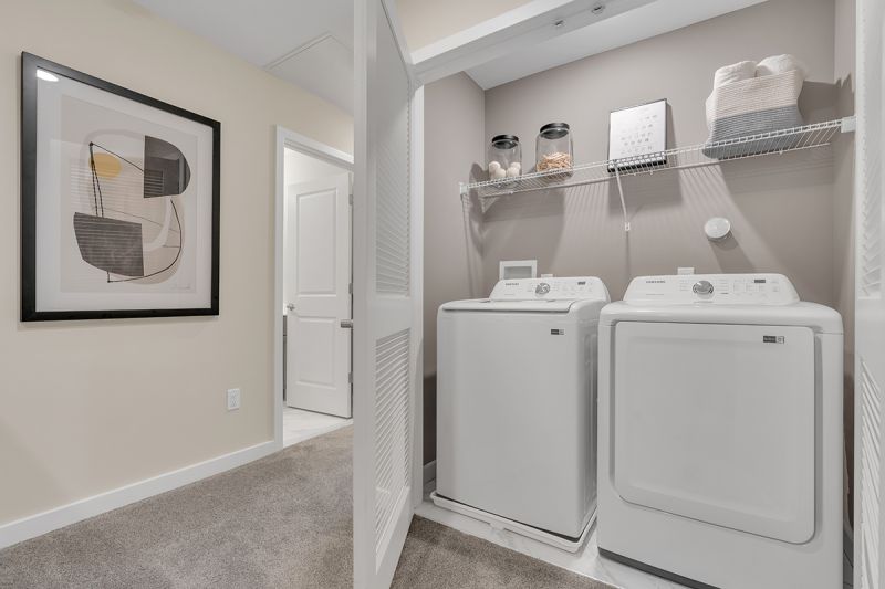 Interior photo of the Boulders at Beekman showing a full size washer and dryer with shelving above for storage, with doors to close to hide them.