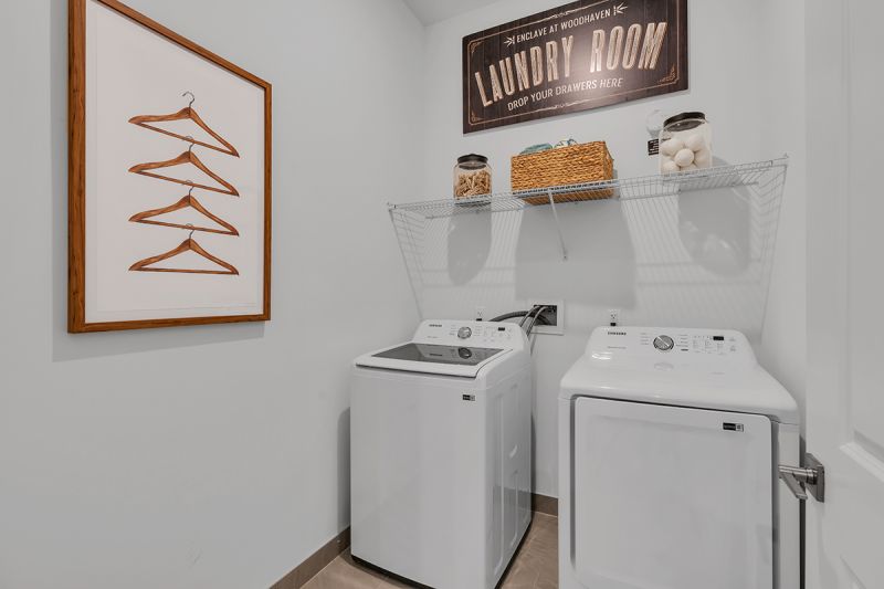 Interior photo of the Enclave at Woodhaven showing a full size washer and dryer with shelving above for storage, with doors to close to hide them.