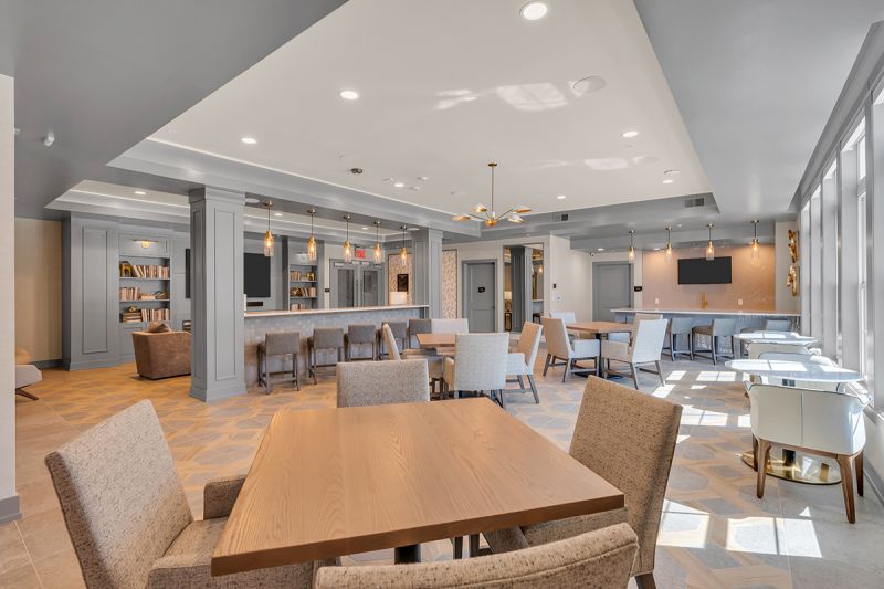 Interior photo of the resident lounge at the Enclave at Woodhaven showing several tables and seating areas of for residents to congregate.