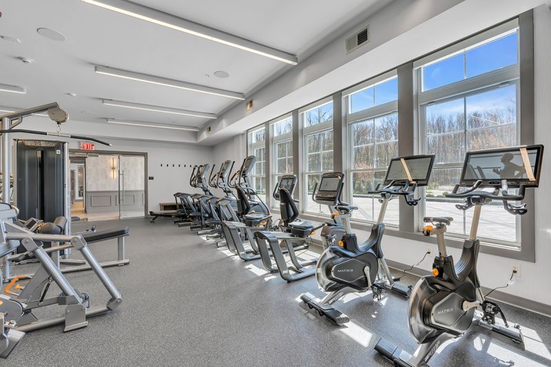 Interior photo of the gym at the Enclave at Woodhaven showing multiple stationary bikes and strength training machines.