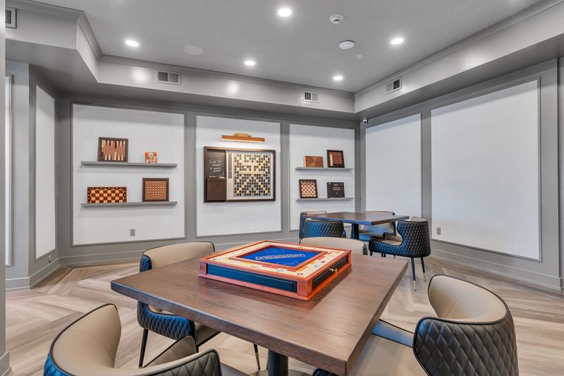 Interior photo of the game room at the Enclave at Woodhaven showing multiple seating areas and games for residents to congregate and have fun.