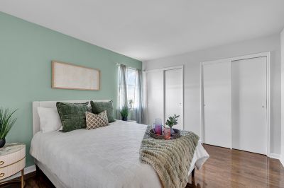 Interior photo of the bedroom at Carteret Garden showing luxury hardwood flooring, a bed with two nightstands on each side, and two large closets with sliding doors. A large window can be seen to allow for natural light.