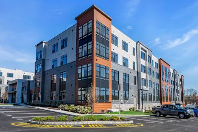 Exterior photo of Woodland Square showing a luxury 4 story apartment building with multiple color finishes and large glass windows.