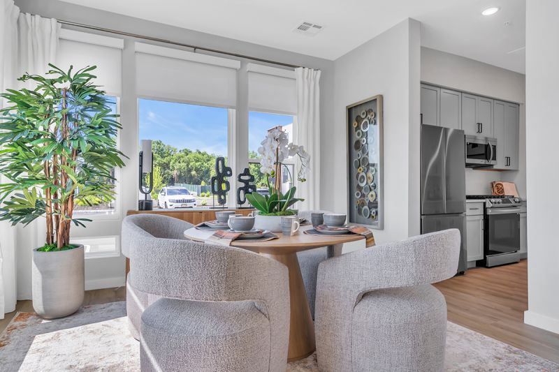 Interior photo of the dining room in Woodland Square featuring a circular table seating 4 people with large floor-to-ceiling windows overlooking the community.