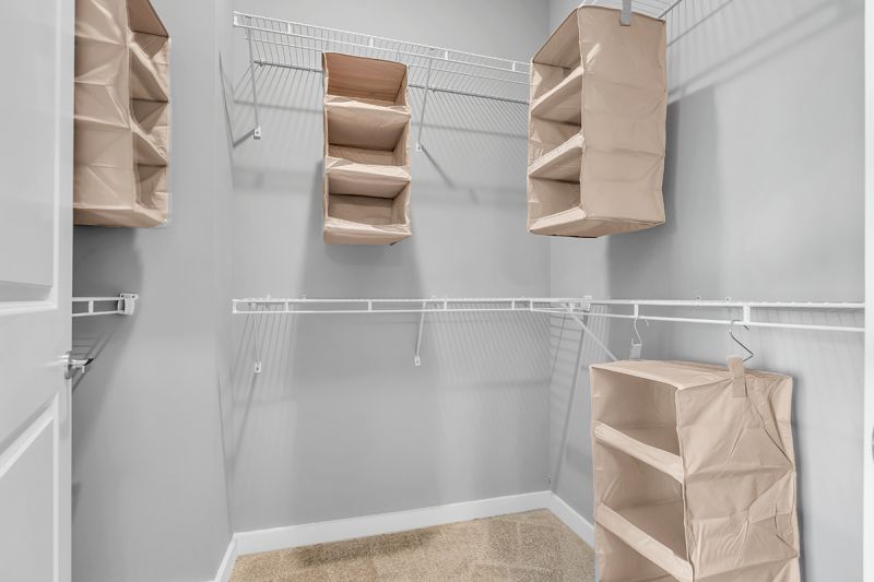 Interior photo at Woodland Square showing the interior of a walk-in closet in the primary bedroom with wire frame shelving and decorative storage bins
