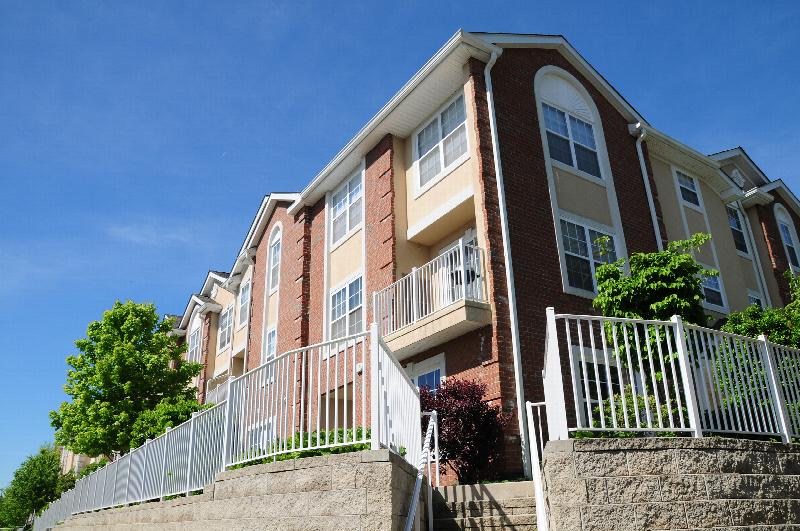 Liberty Terrace building exterior photo showing a balcony, retaining wall with stairs, and a white fence.