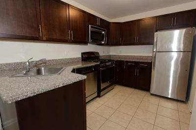 Interior photo of a refurbished kitchen at Liberty Terrace, showing new tile floors, cherry cabinets, granite countertops and stainless steel appliances