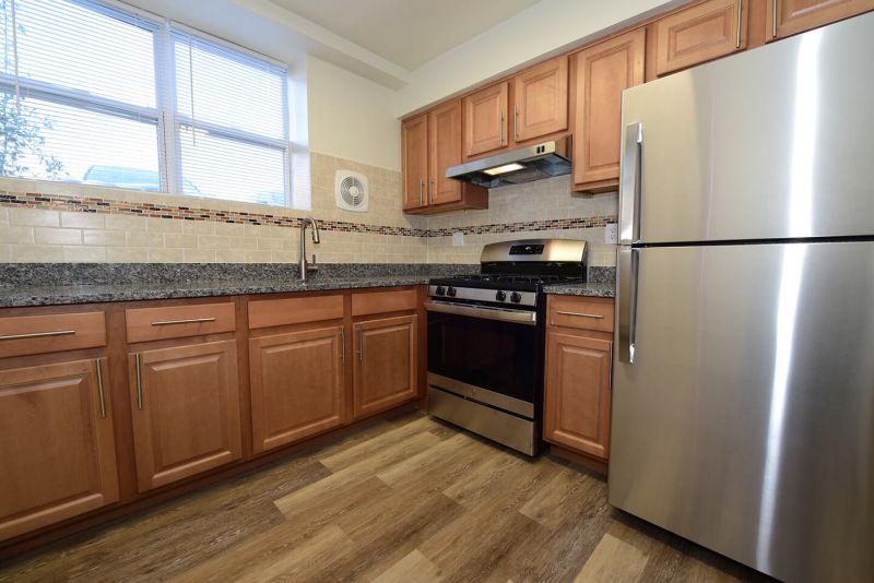 Photo of renovated kitchen showing wood grain tile flooring, new cabinets with granite counter tops and a stainless steel appliance package.