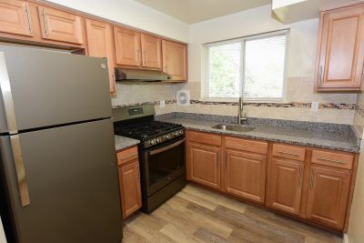 Photo of renovated kitchen showing wood grain tile flooring, new cabinets with granite counter tops and a stainless steel appliance package.