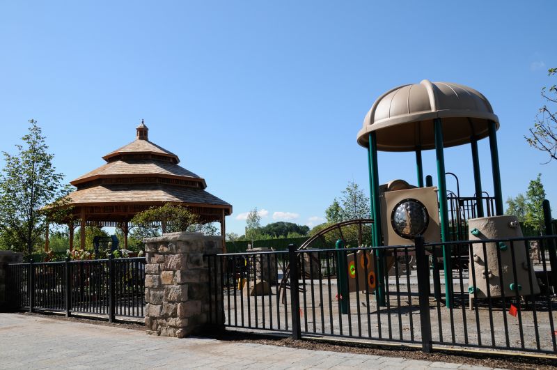 Helix at Xchange exterior photo shows fenced in community courtyard with gazebo and children’s playground. Tree lined streets can be seen in the background. 