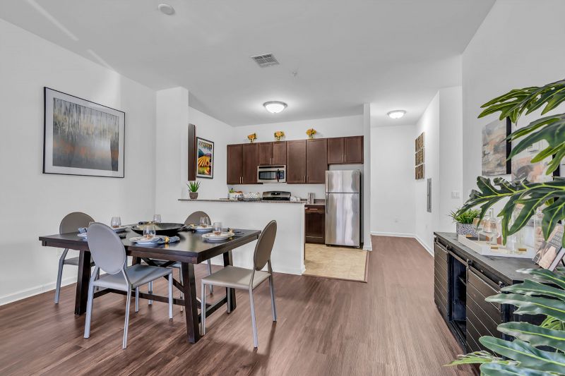 Interior photo of a model at Helix at Xchange showcasing the open-concept design of the kitchen and dinette area. The space features elegant hardwood flooring, a four-person dinette with table and chairs, and a side console offering additional storage.