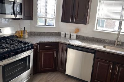 Edison Woods photo of a renovated kitchen showing woodgrain flooring, new cabinets, granite countertops and stainless steel appliances.