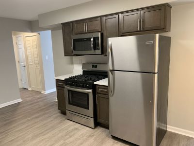 Photo of a renovated apartment at Rivendell at Edison showing a kitchen with new cabinets and countertops, stainless steel appliances, and luxury vinyl woodgrain tile.