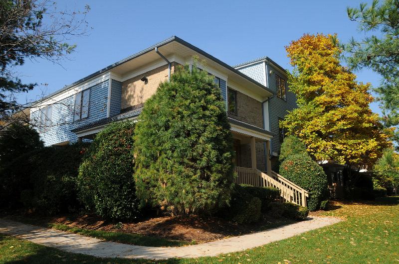Peach Street Exterior photo showing a brick and vinyl exterior and an apartment entrance. Several bushes and trees highlight the landscape.