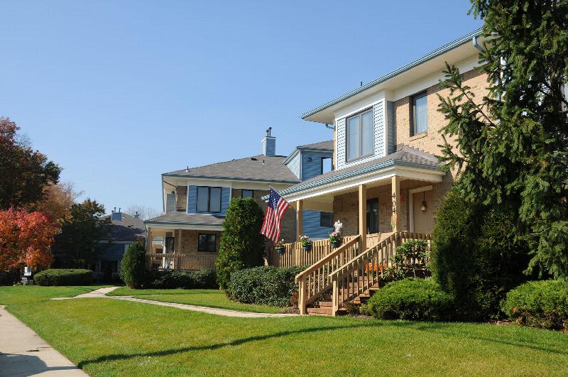 Peach Street Exterior photo showing a brick and vinyl exterior and an apartment entrance. Several bushes and trees highlight the landscape.