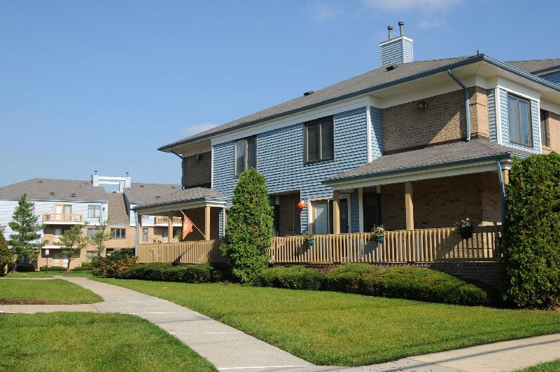 Peach Street Exterior photo showing a brick and vinyl exterior and several balconies. Several bushes and trees highlight the landscape.