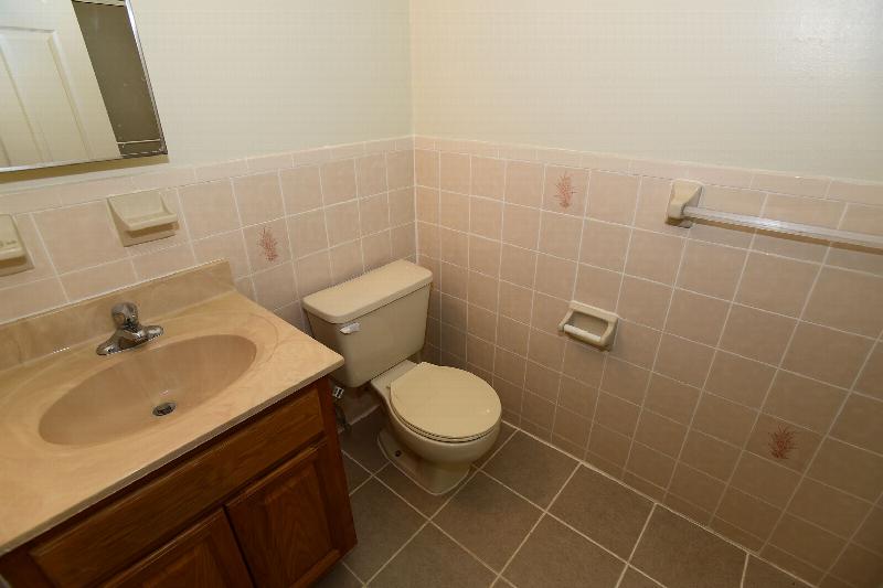 Peach Street Bathroom photo showing a maple cabinet with a sink, tile flooring and a toilet.