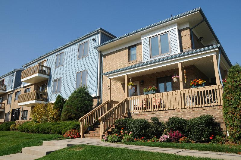 Peach Street Exterior photo showing a brick and vinyl exterior and several balconies. Several bushes and trees highlight the landscape.