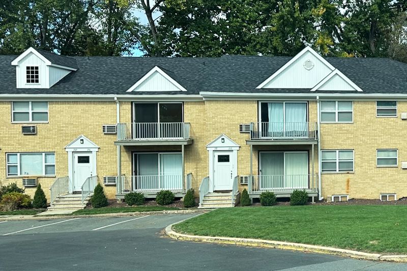 Exterior photo of Delaware Heights showing a 2 story brick building with balconies and a new roof. Landscaping in front of the buildings character