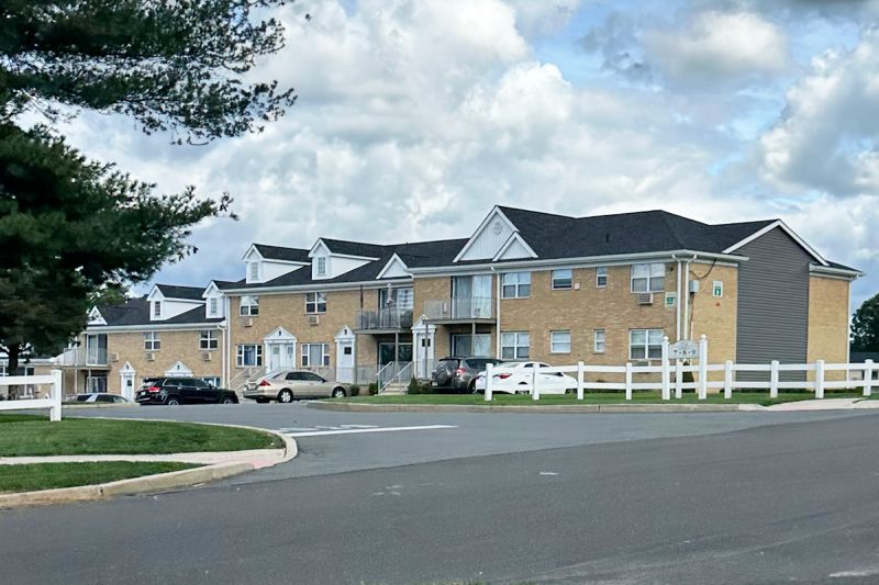 Exterior photo of Delaware Heights showing a 2 story brick building with balconies and a new roof. Landscaping in front of the buildings character