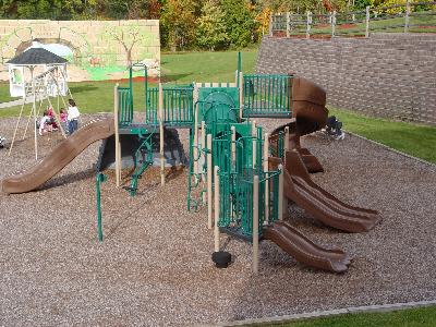 Sun Valley community playground area showing a large piece of children’s play equipment with multiple slides, a swing set, and benches.