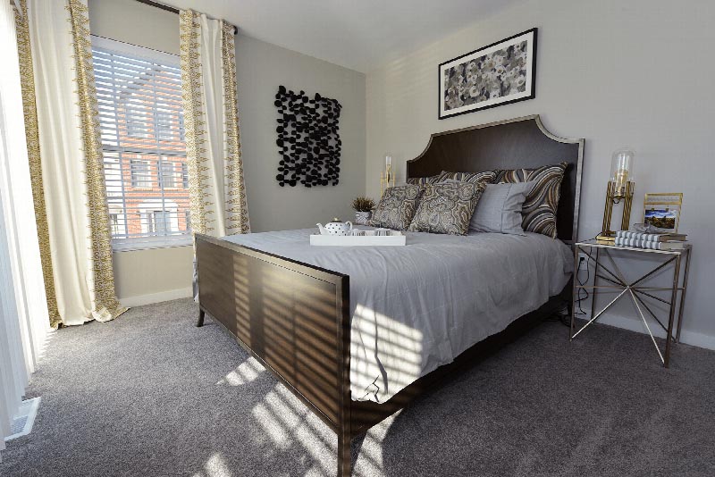 Sun Valley Plaza photo of a bedroom showing a queen sized bed with two end tables. The room has plush wall to wall carpeting and several windows to allow for natural light.