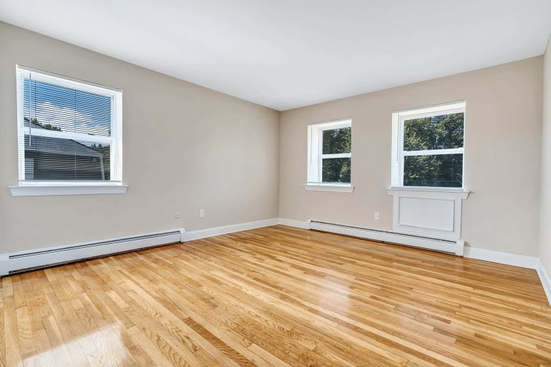 Interior photo of a refurbished bedroom at Beekman Gardens in Hillsborough, NJ showing fresh paint, refinished hardwood floors and several windows to allow for natural light.