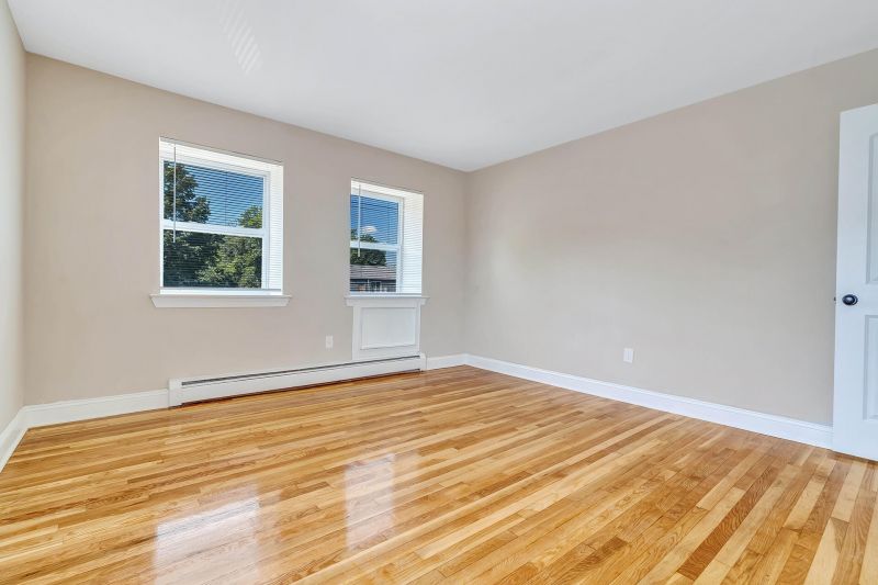 Interior photo of a refurbished bedroom at Beekman Gardens in Hillsborough, NJ showing fresh paint, refinished hardwood floors and several windows to allow for natural light.