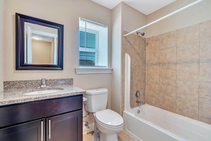 Interior photo of a refurbished bathroom at Beekman Gardens in Hillsborough, NJ showing fresh paint, new tile, new tub, new toilet, new sink, vanity and mirror.
