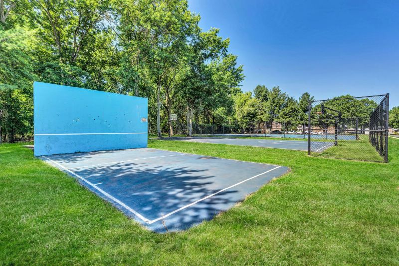 Exterior photo of Beekman Garden in Hillsborough, NJ showing the community handball court, surrounded by grass and trees.