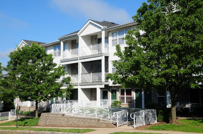 Tyler Greens apartments photo of the exterior shows a three level apartment building with balconies. Several large green trees offer shade and privacy.