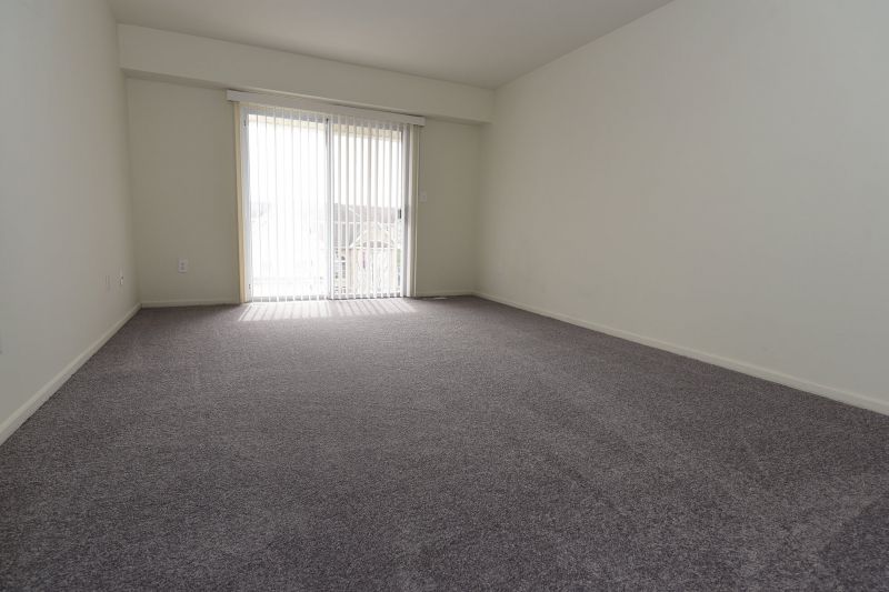 Photo of bedroom at Tyler Greens showing new carpeting, freshly painted walls and a sliding glass door leading out to a balcony.