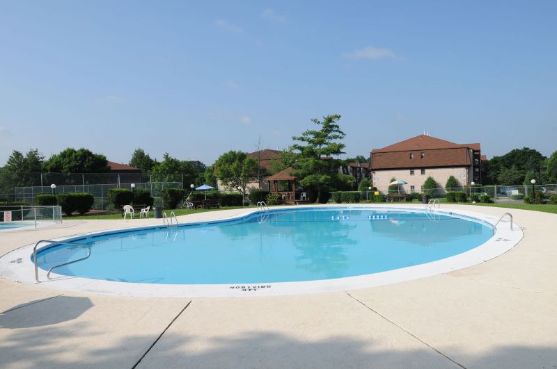Green Plaza community swimming pool photo showing crystal clear water and a cement patio area surrounding the pool.