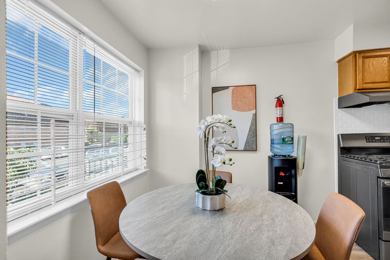 Interior photo of the eat-in kitchen at Green Plaza showing a four-person seating area with a large window to allow natural light.