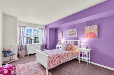 Interior photo of the bedroom at Green Plaza showing a twin-size bed, two nightstands, and a dresser with wall-to-wall carpeting. Large window to allow for natural light.