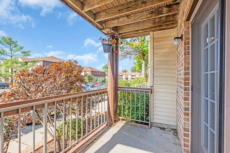 Exterior photo of the balcony at Green Plaza showing wood railings that overlooks lush landscapes of the entire community.